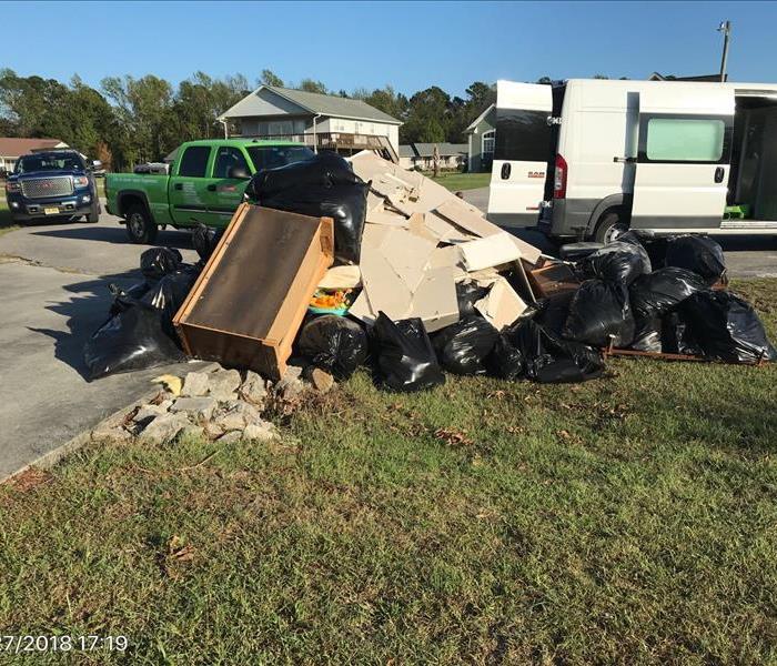 construction debris on a lawn with trucks parked on the street